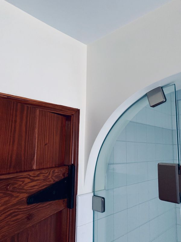 Wooden door and glass shower door with curved drywall.