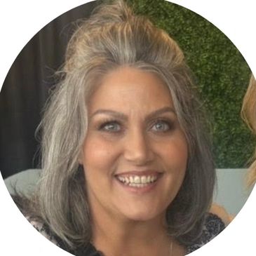 Smiling woman with gray hair and bright eyes.