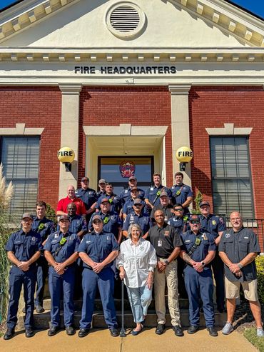Group photo of firefighters and community members in front of fire headquarters.