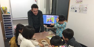 A teacher engaging children in a classroom activity around a table.