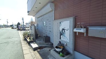 Street view of a building with shuttered doors and wall art.