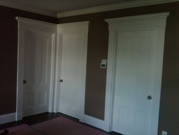 Three white paneled doors on brown walls with white trim.