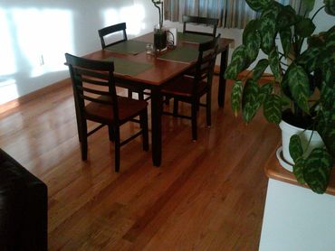 Wooden dining table with four chairs on a polished floor.