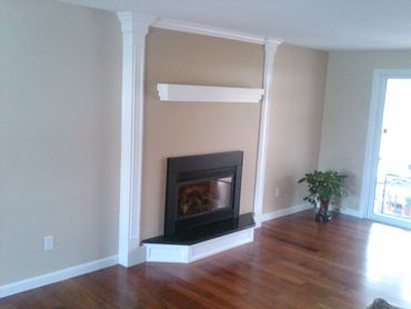 Modern corner fireplace with white trim and hardwood floors.