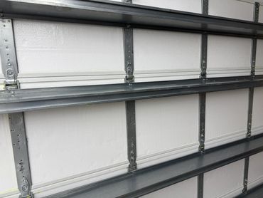 Close-up of a white garage door with metal hinges and rails.