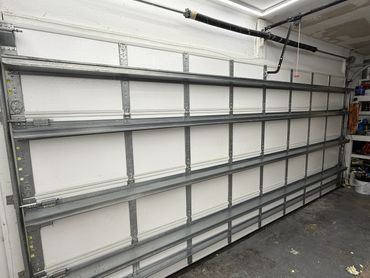Interior view of a closed white garage door with metal reinforcements.