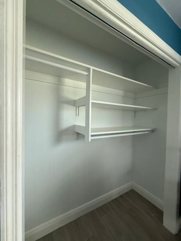 Empty white closet with shelves and hanging rods.