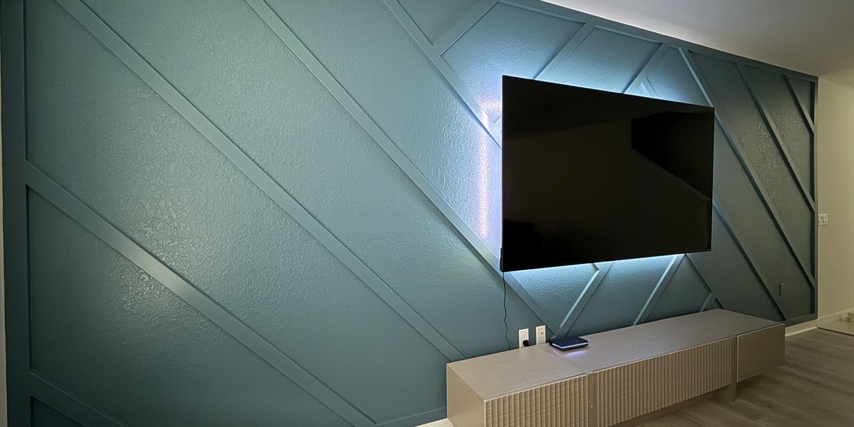 Modern TV mounted on a stylish blue accent wall with geometric patterns.
