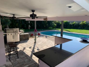 Outdoor patio with bar, grill, and swimming pool in a sunny backyard.