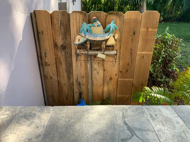 Decorative wooden fence with tropical-themed 'Island Time' sign and lush garden surroundings.