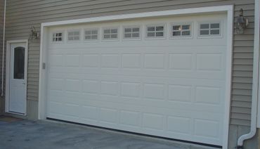 White garage door with windows on a beige house exterior.