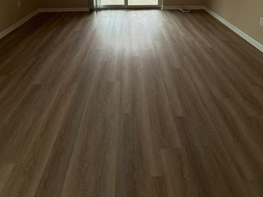 Empty room with newly installed light brown wood flooring and natural light.
