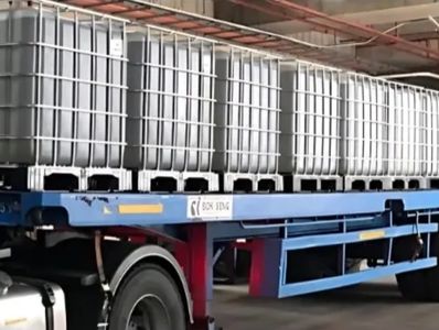 Large industrial containers loaded on a blue flatbed truck.
