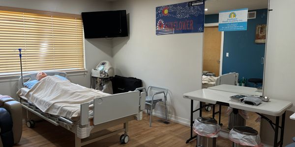 Medical training room with a hospital bed and mannequin for practice.