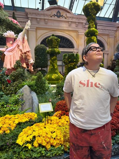 Person in garden setting wearing a 'She.' t-shirt.