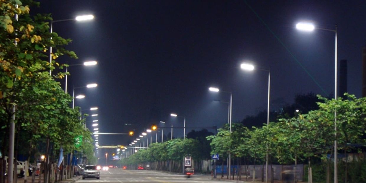 A well-lit street at night with trees along the roadside.