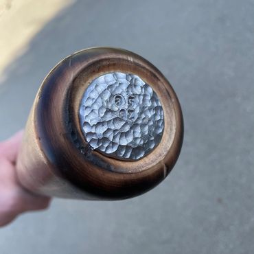 Close-up of a wooden object with a hammered metal cap.
