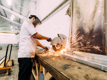 Worker cutting metal with sparks flying in a workshop.