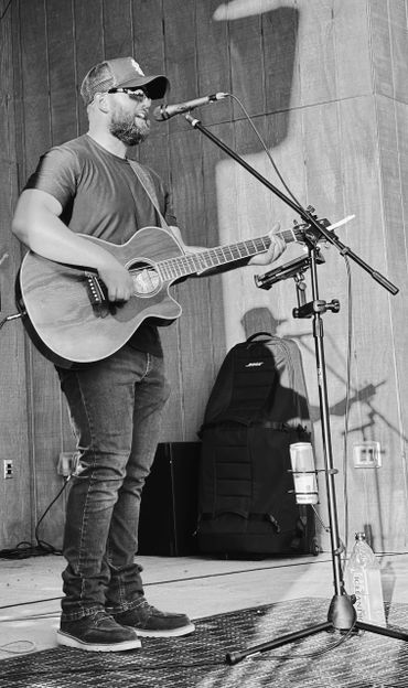 Musician playing guitar and singing on stage.
