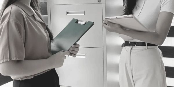 Two people holding clipboards, engaged in discussion.