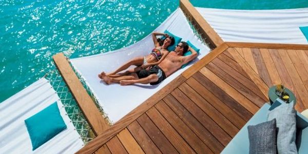 Couple lounges on a hammock over the water