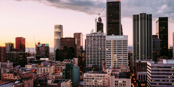 City skyline at dusk with illuminated buildings and a purple sky.