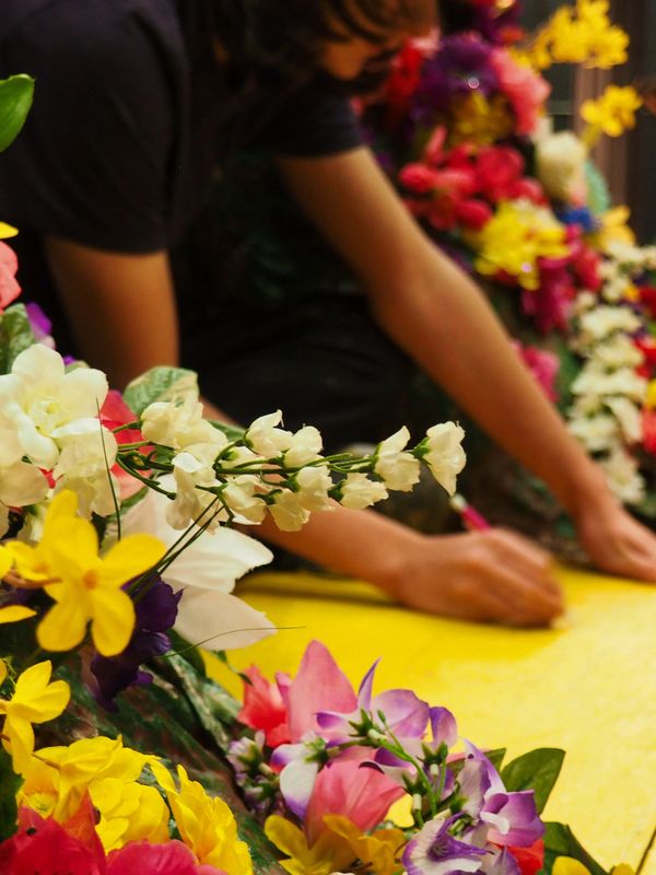 The hands of a technician putting the finishing touches on a yellow bridge covered in flowers.