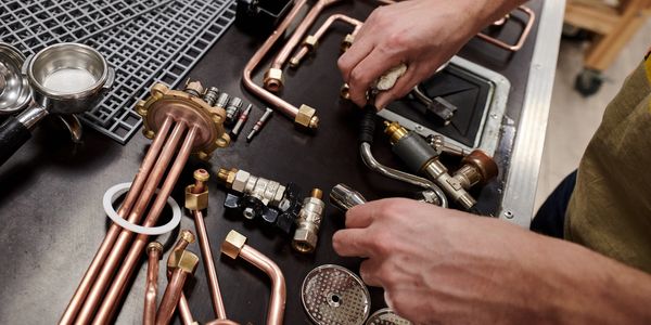 Hands assembling copper plumbing parts on a table.