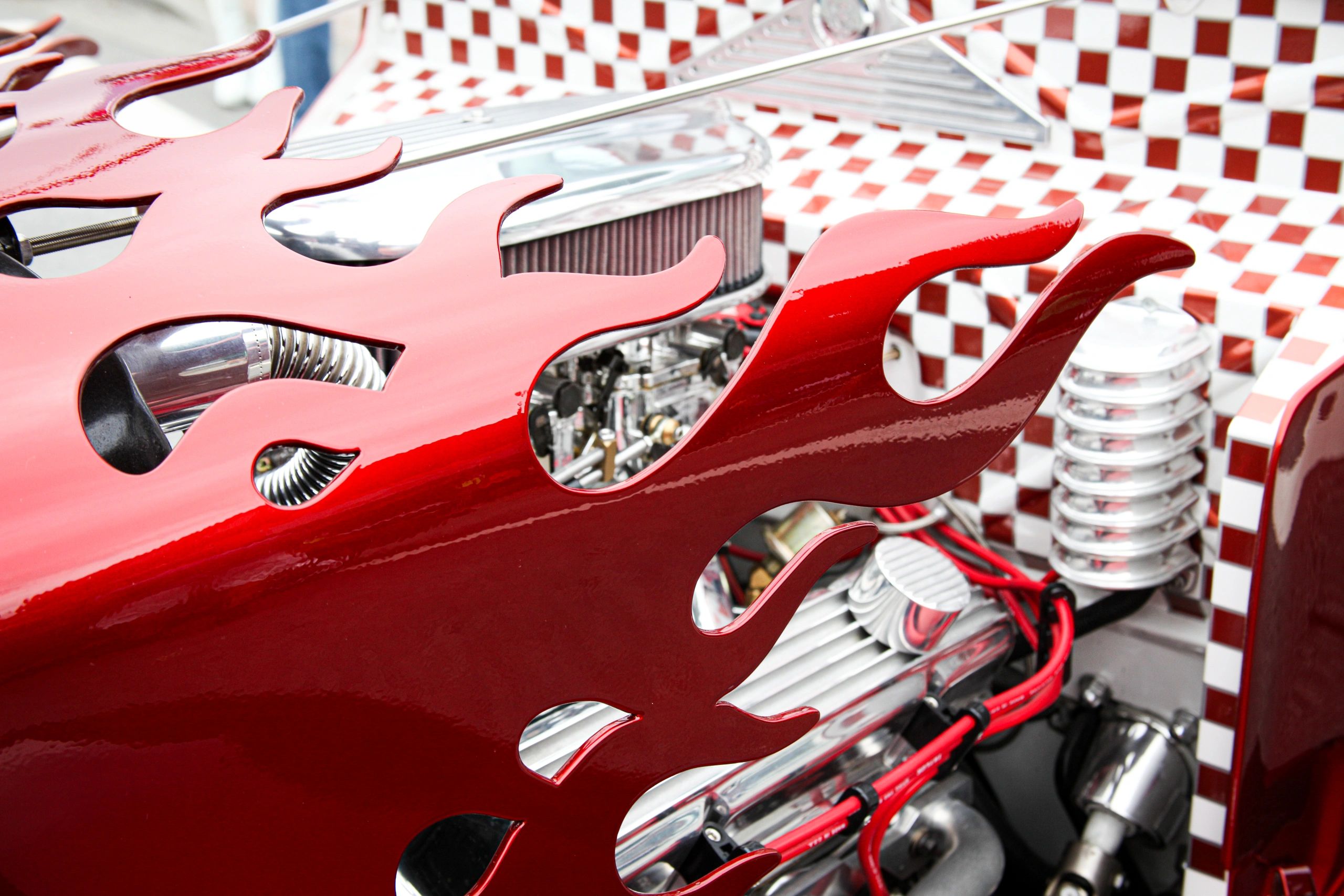 Close-up of a custom car engine with red flame design and checkered pattern.
