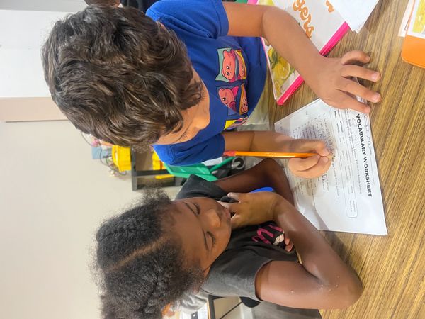 Two children working on a vocabulary worksheet.