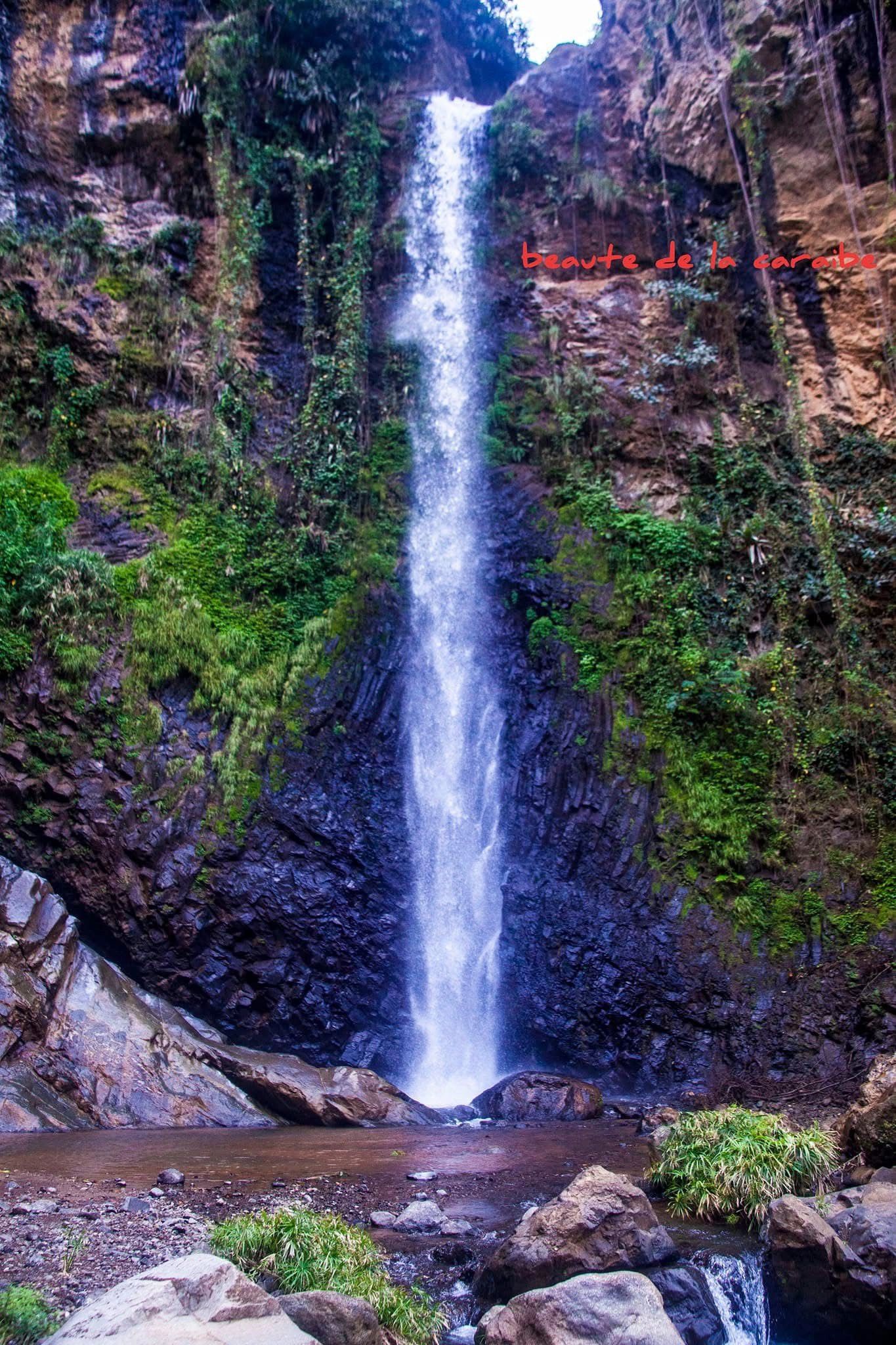 A tall waterfall cascading down a rocky, green cliff.