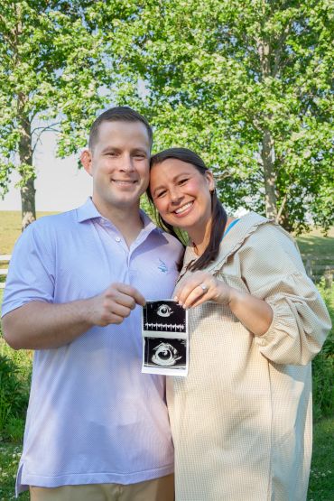 Couple happily holding ultrasound images outdoors.