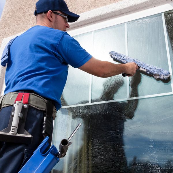 A man cleaning a large window with a squeegee.