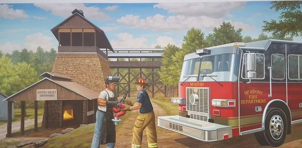 Firefighter receiving equipment from a welder outdoors.