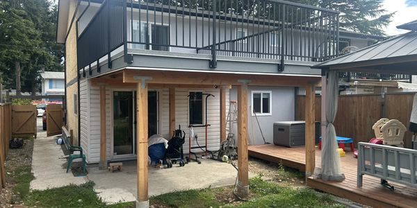 Backyard of a two-story house with a patio and wooden deck.