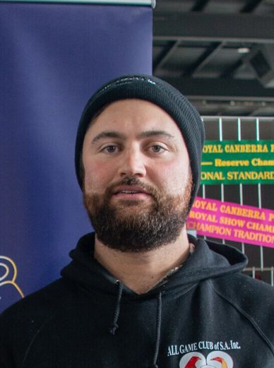 Bearded man in a black beanie and hoodie at an event.