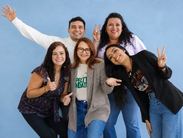 Group of five happy friends posing with peace and thumbs up signs.