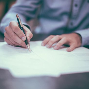 Person writing on paper with a pen.
