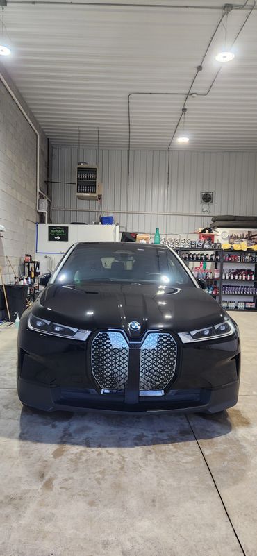 Front view of a black BMW in a garage with shelves in the background.