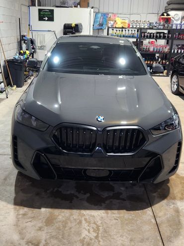 Gray BMW parked inside a garage with shelves of car care products.