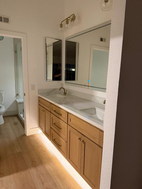 Double white oak vanity in Temecula, CA. Large mirror above vanity. Quartz countertops. 