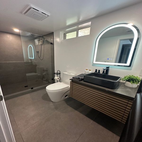 Floating vanity in guest bathroom by Justice Renovations. Infinity niche in shower. Vessel sink