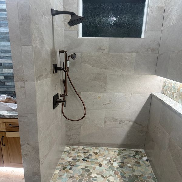 Light up niche in shower. Oil rubbed bronze finishes in shower. Pebble tile floor in shower. 