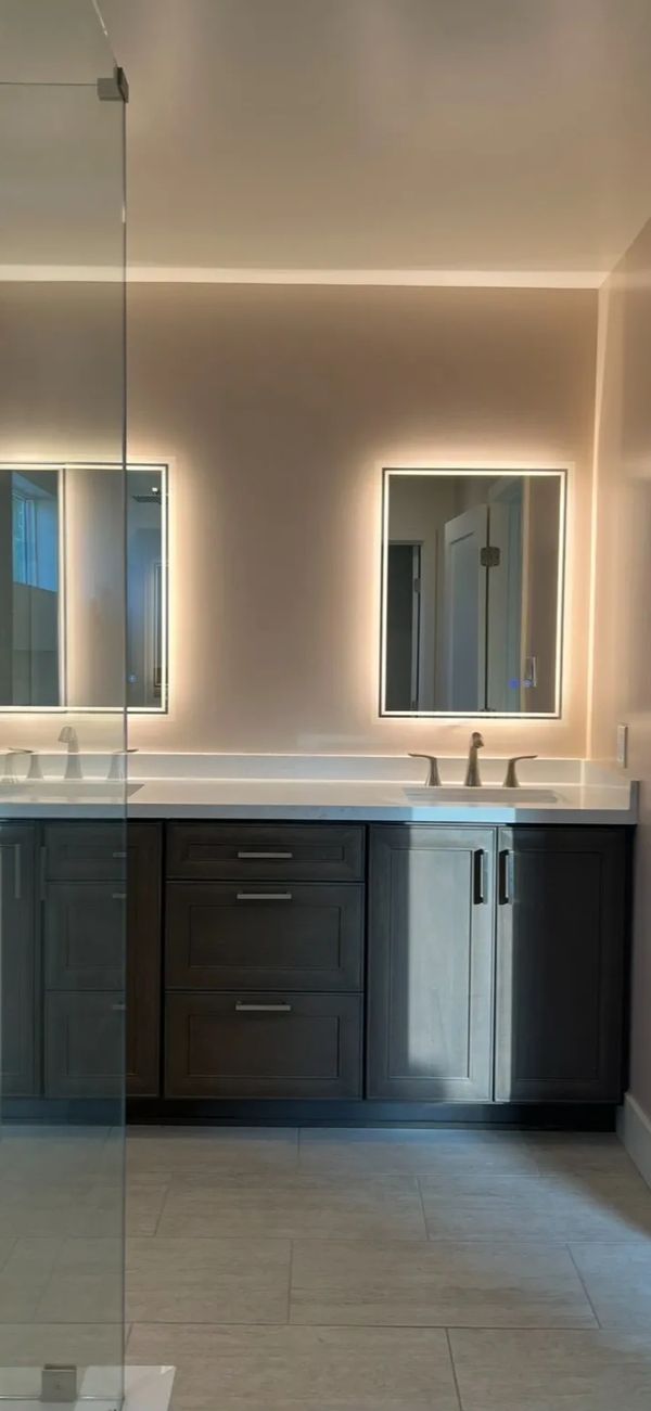brown cabinetry in master bathroom. Light up mirrors at vanity. 