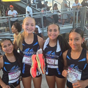 Four young female athletes in matching Thunder uniforms posing after a race.