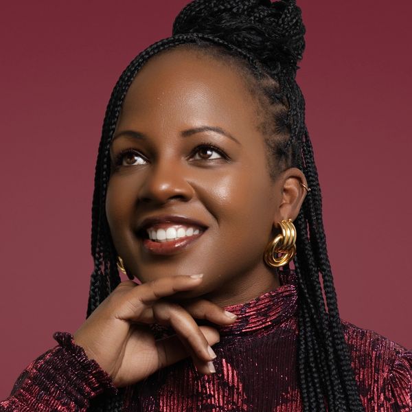 Woman smiling with braided hair and gold earrings.