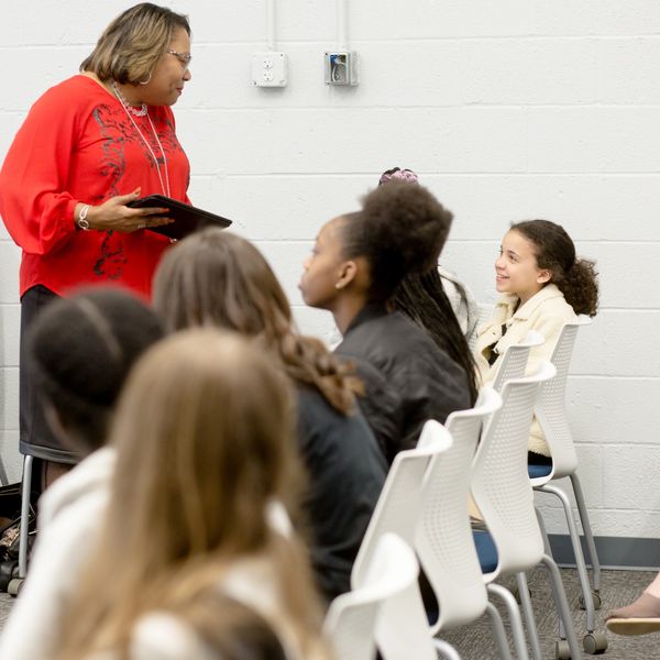 Teacher engaging with attentive students in a classroom setting.