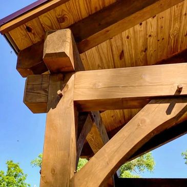 Close-up of wooden beams and joints under a roof against a clear blue sky.