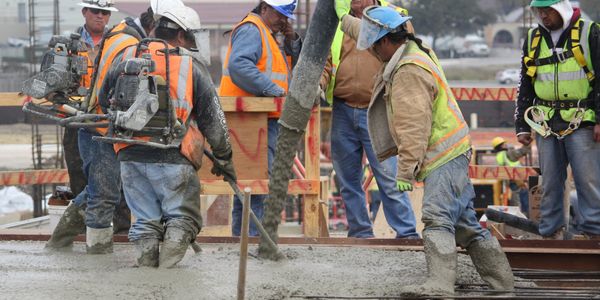 Construction workers pouring and leveling concrete on a building site.
