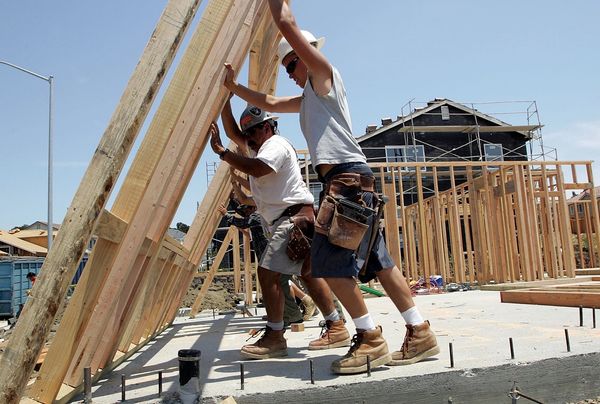Construction workers lifting a wooden frame on a building site.